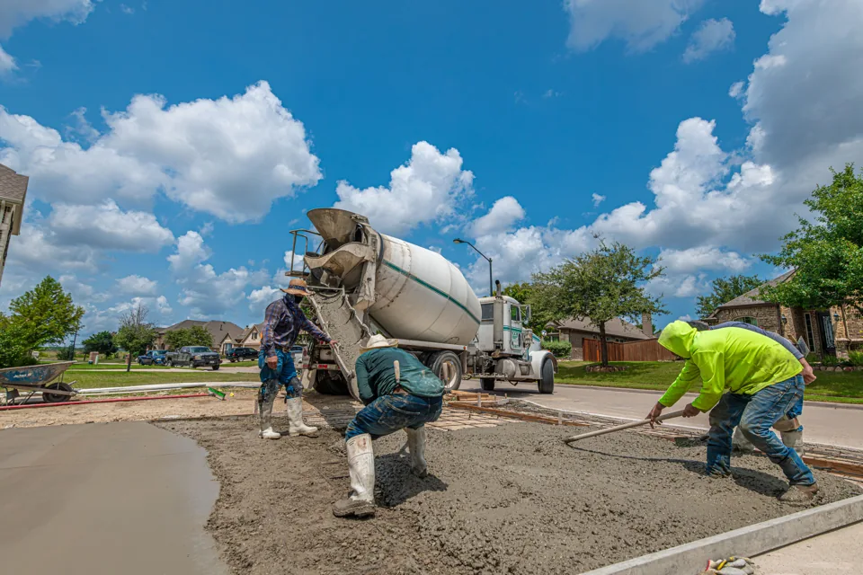 Workers placing new residential driveway concrete in a representative construction scene