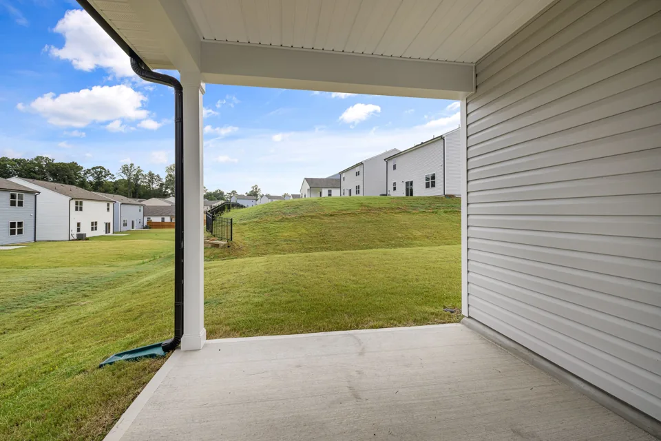 Residential concrete patio beside a covered porch and lawn